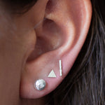 Brunette model ear close up of pebble, triangle and bar silver stud earrings
