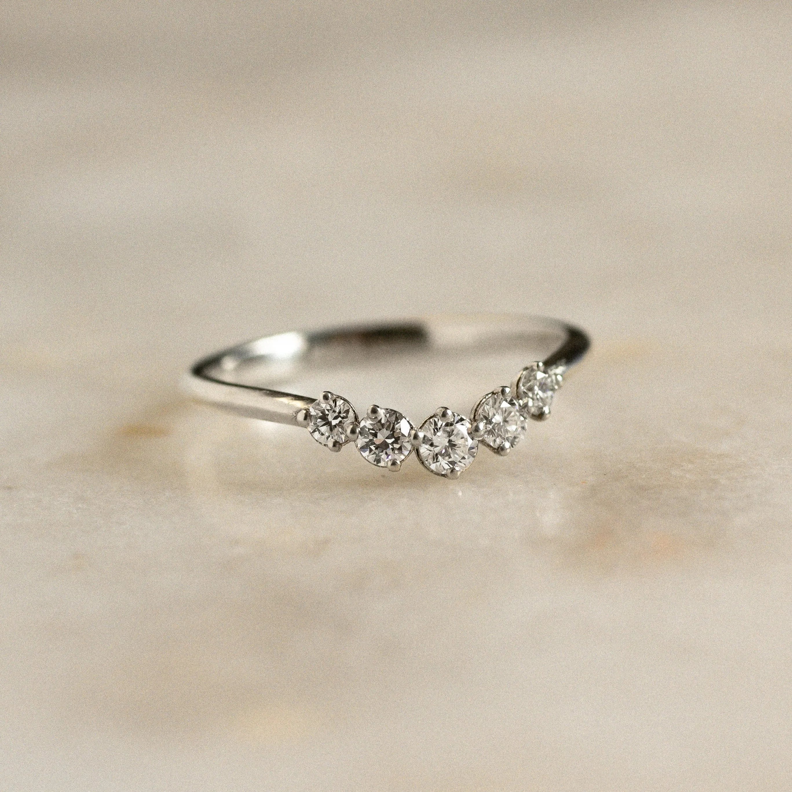 white gold nesting wedding ring with 5 round diamonds on marble surface