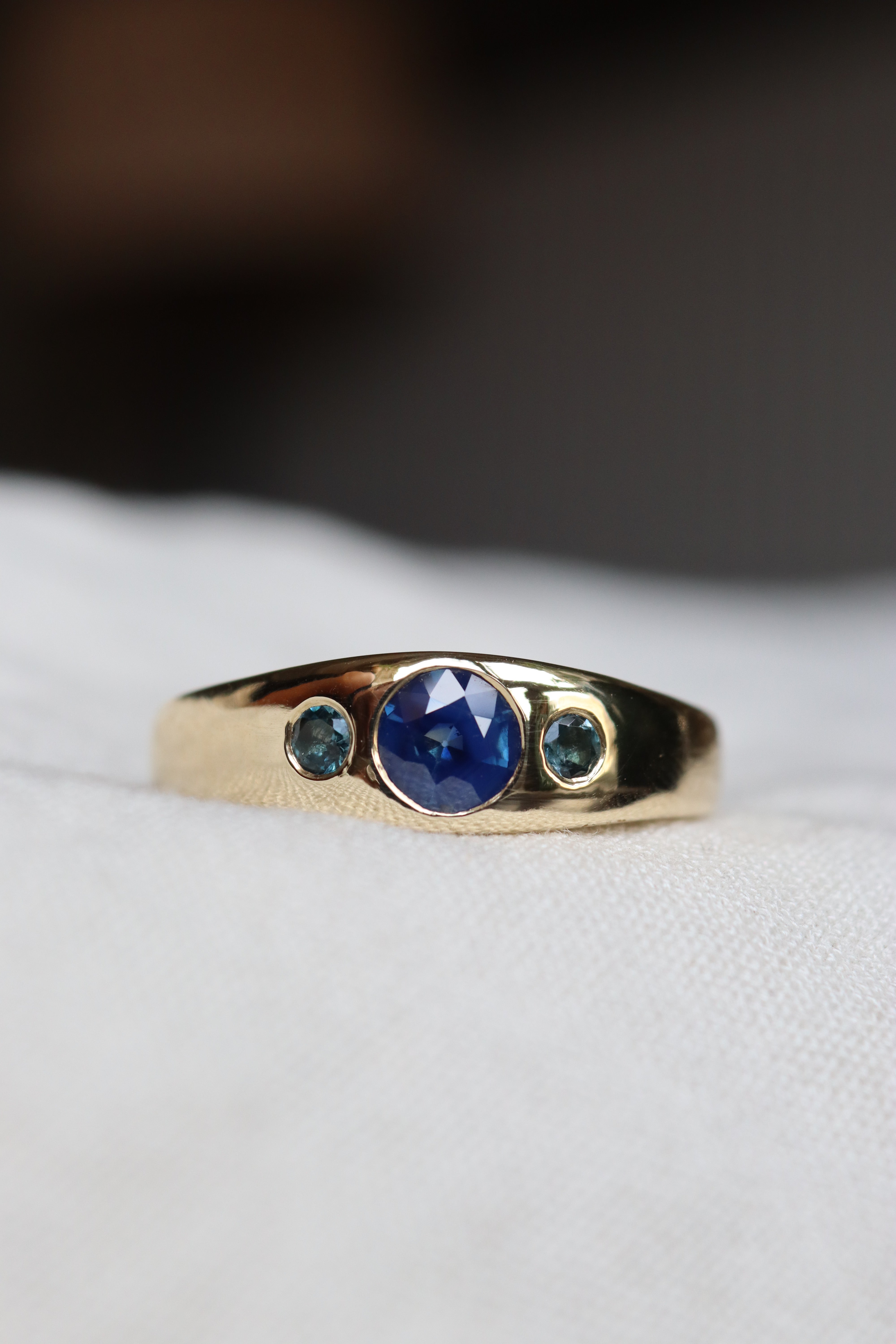 Gold ring with blue gemstones on a white background