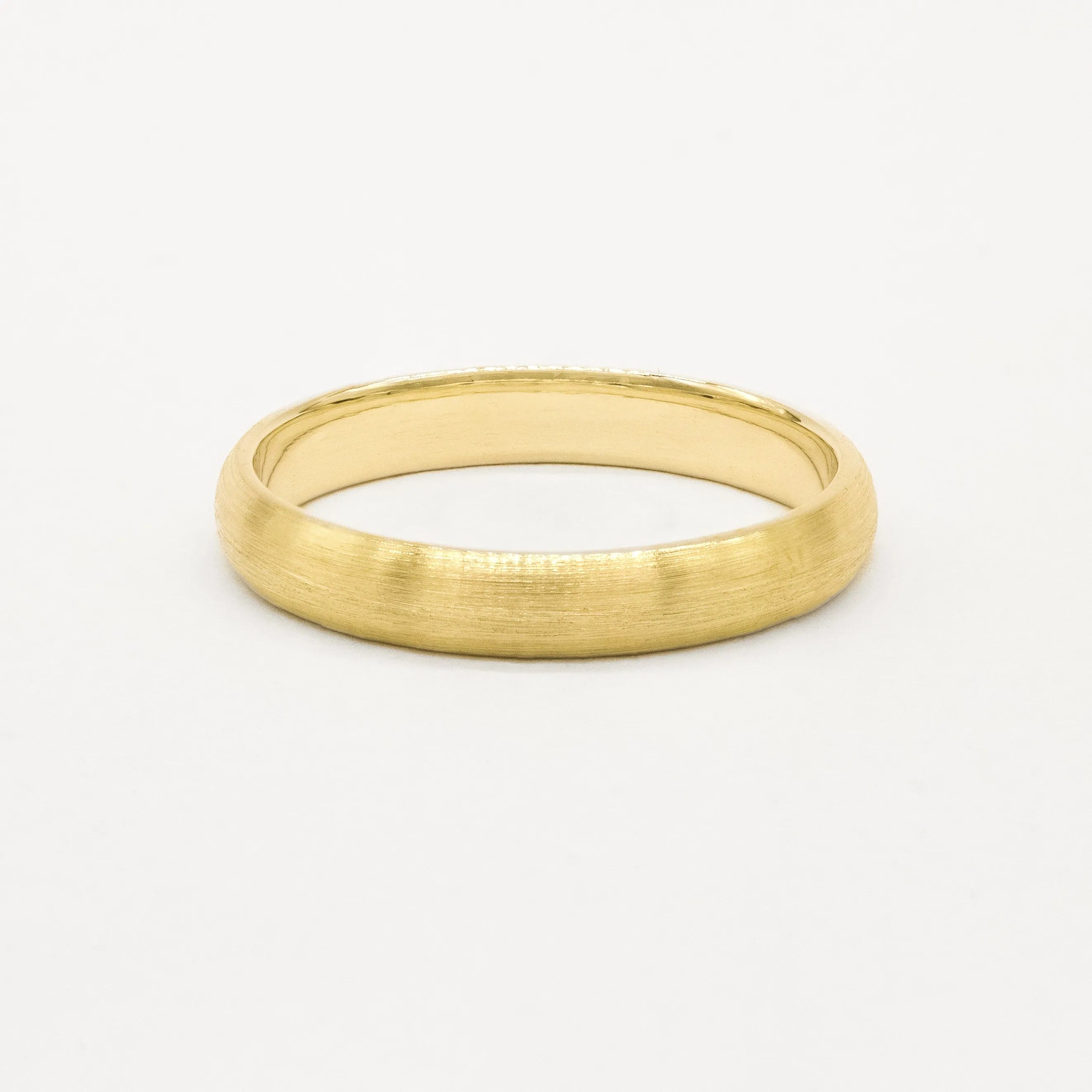 4mm wide yellow gold brushed wedding ring on a light gray background