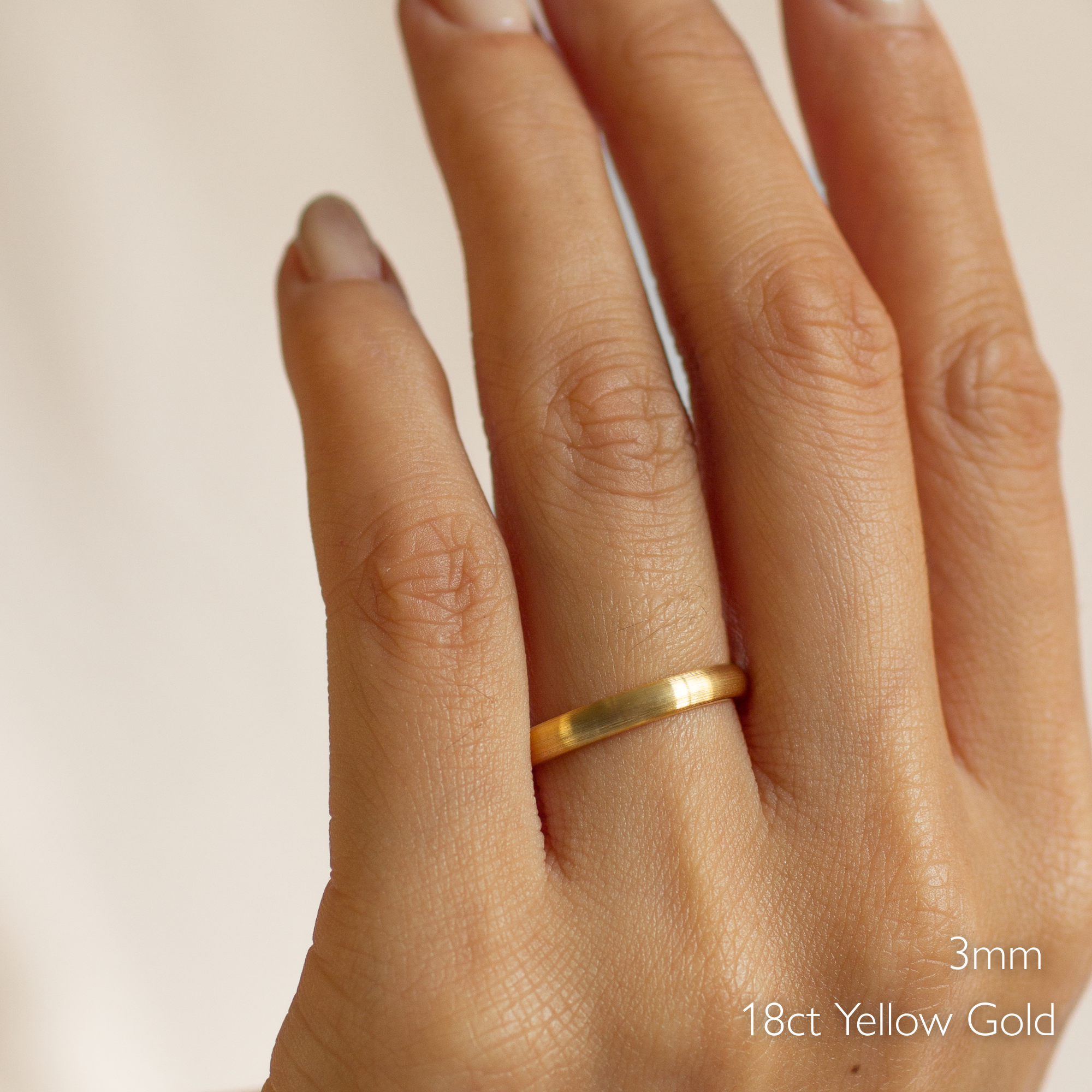 Gold brushed wedding ring on a hand with '3mm' and '18ct Yellow Gold' text.