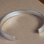 close up of silver bangle with the message 'i love you dad' stamped on the inside