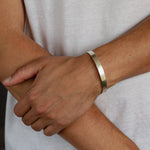 man wearing chunky hammered silver bangle, holding onto his arm