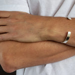 close up of mens crossed arms wearing hammered silver chunky bangle