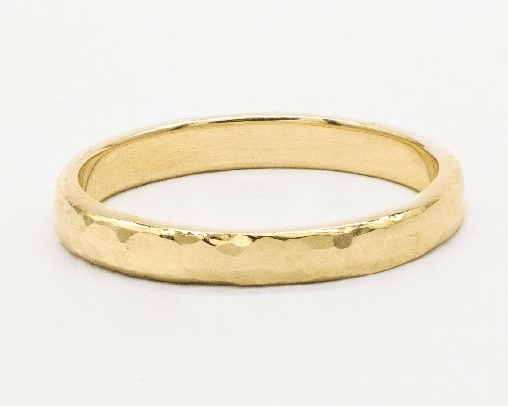 Gold ring with chunky hammered texture on a white background