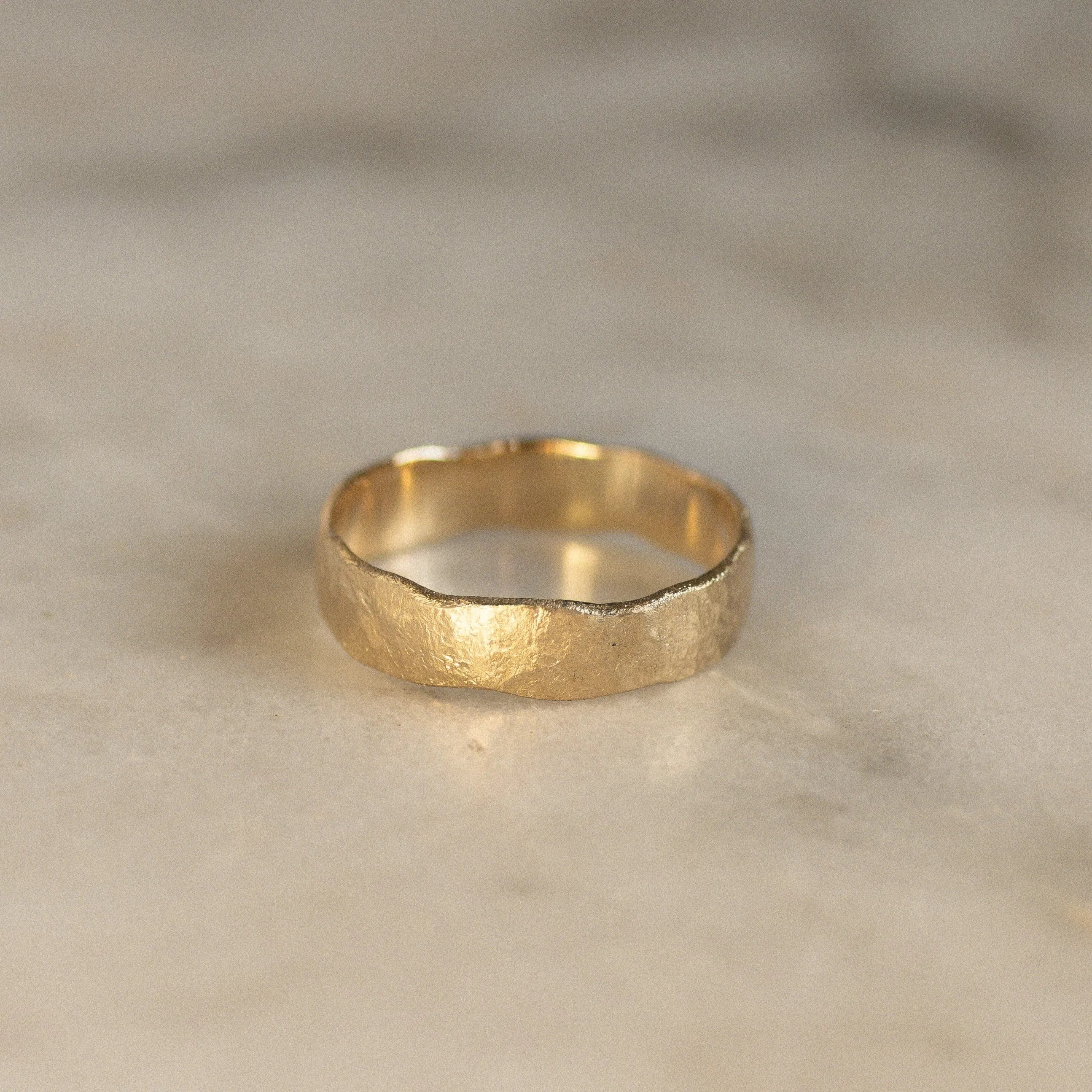 rustric wedding ring with uneven edges on marble surface