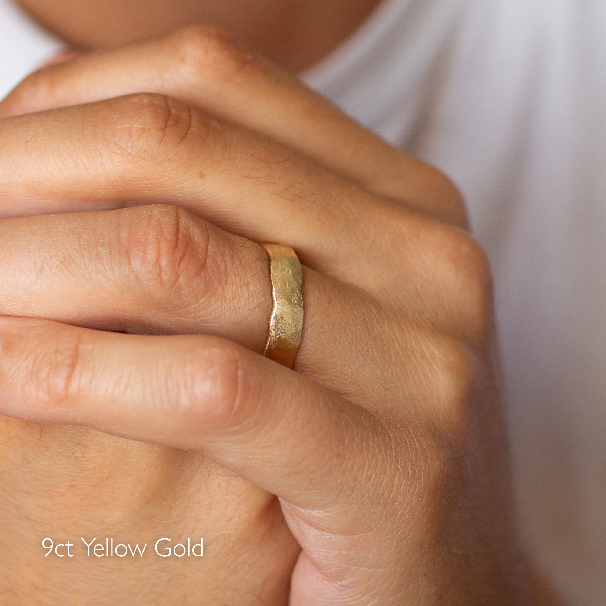 Gold ring on a person's finger with '9ct Yellow Gold' text