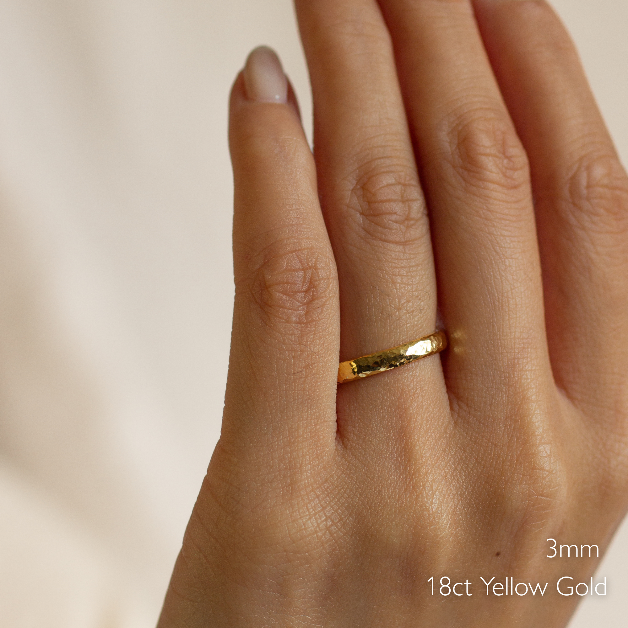 Gold ring with dainty hammered texture on a finger with '3mm 18ct Yellow Gold' text.
