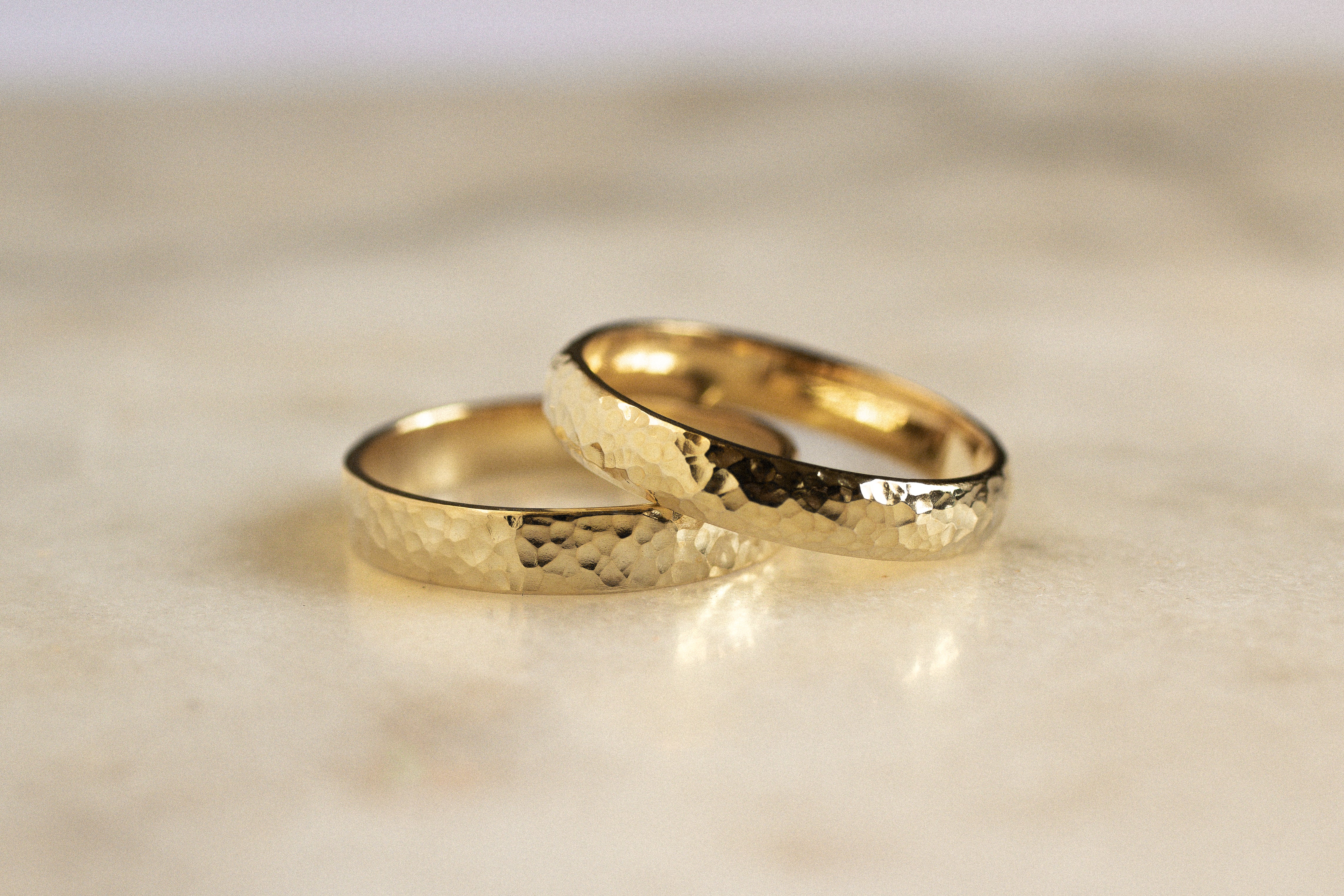 two gold wedding rings in flat and d shapes with dainty hammered texture