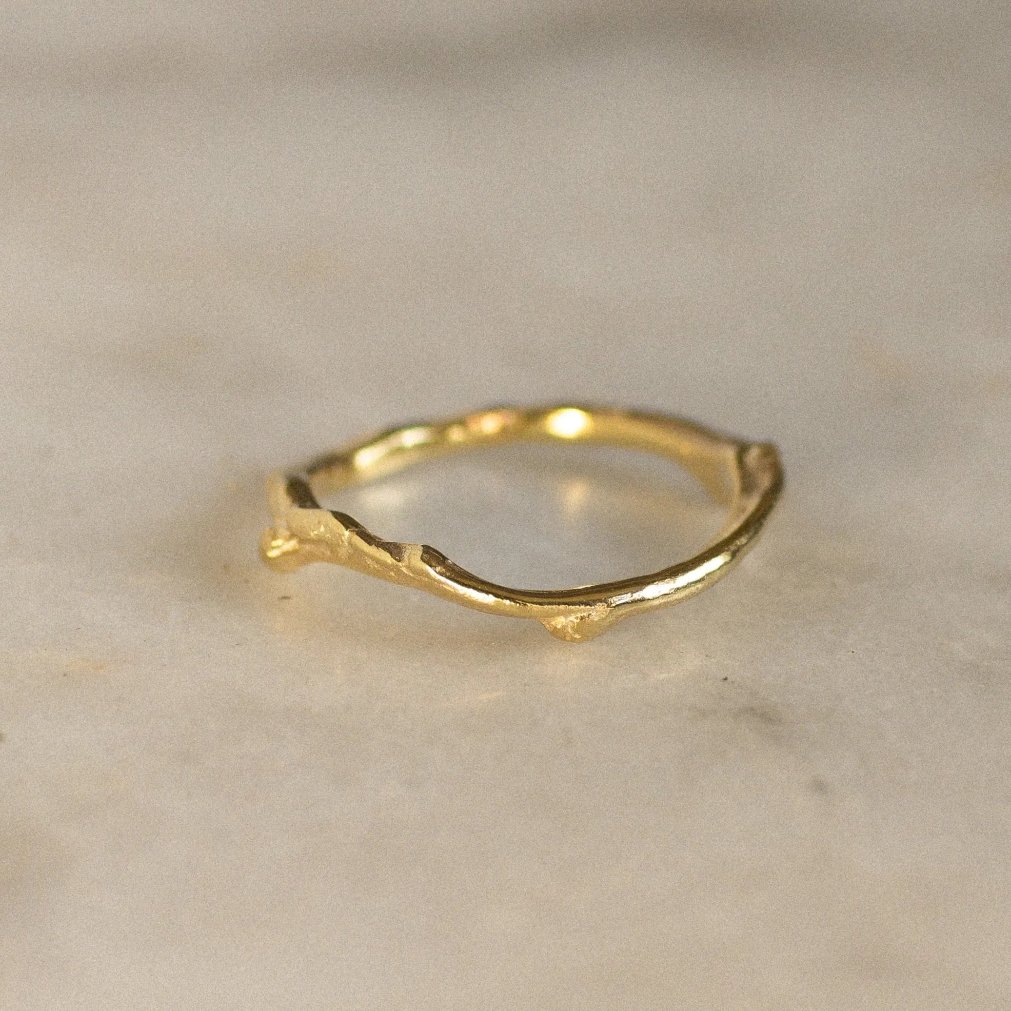 Gold tree branch ring on a marble surface
