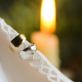 silver and gold textured organic ear cuff on lace fabric with blurred candle in the background