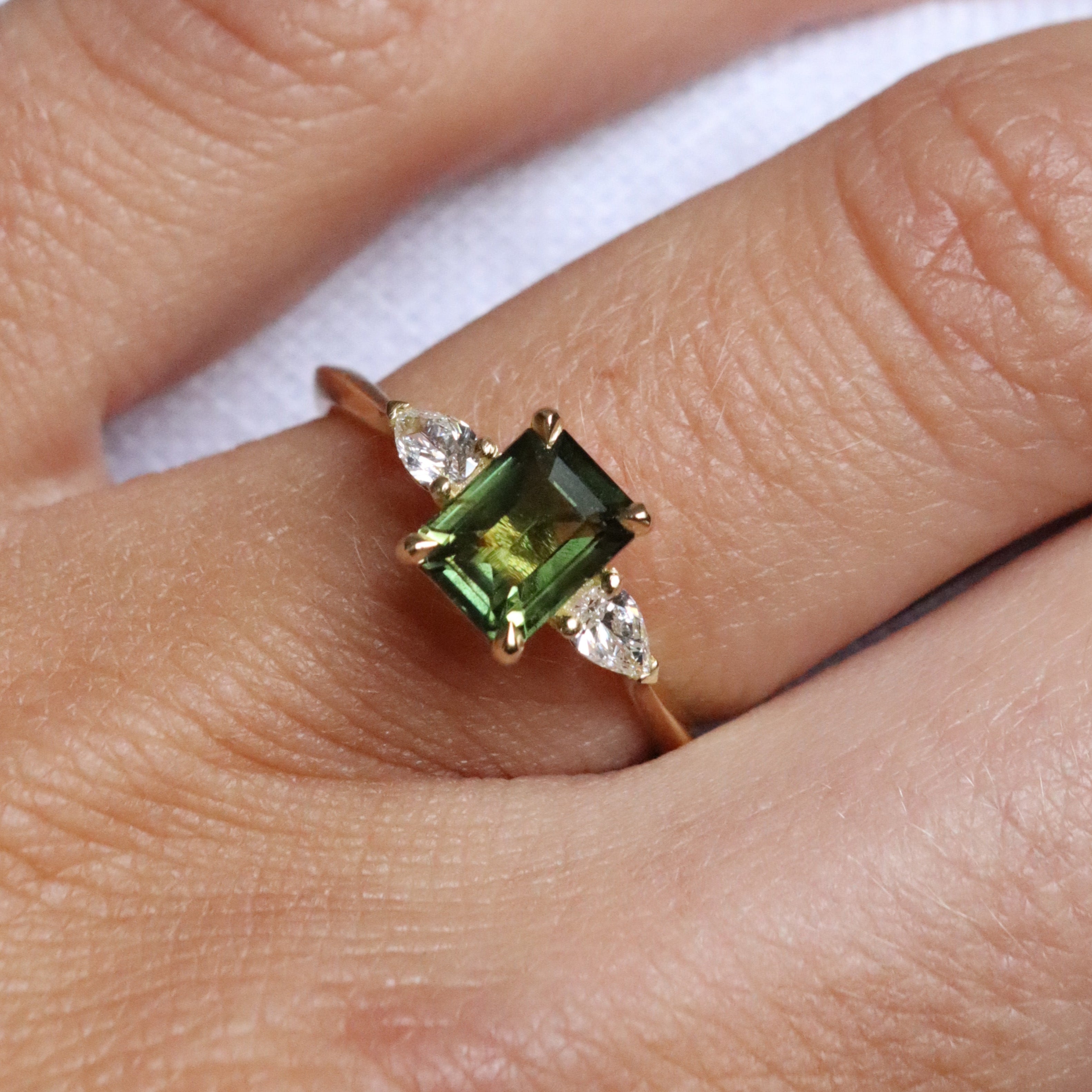 emerald cut green sapphire trilogy engagement ring with pear diamonds