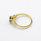 top view of gold engagement ring with green stone and round diamonds