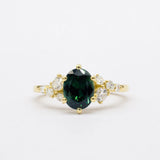 Gold ring with a green gemstone and smaller diamonds on a white background