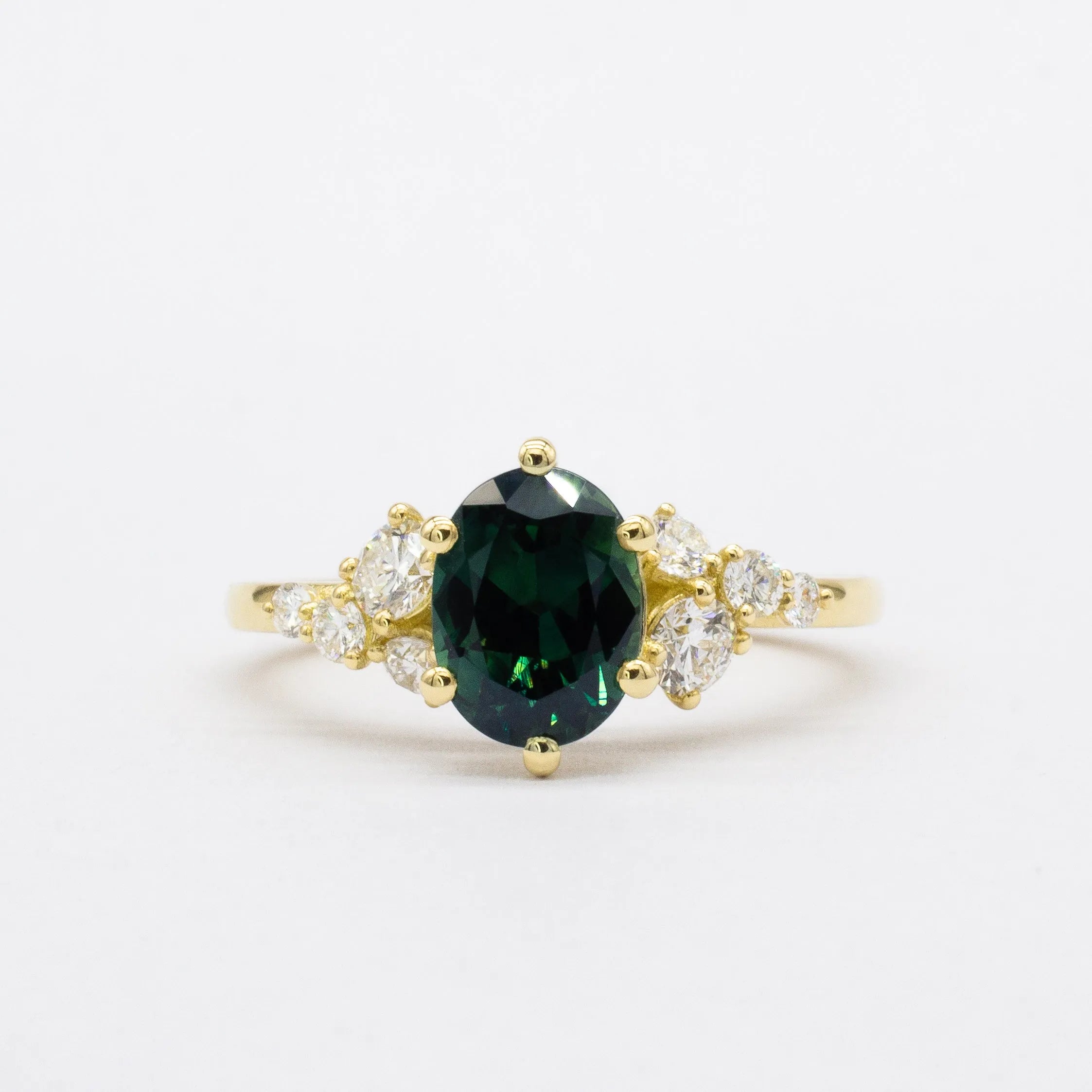 Gold ring with a green gemstone and smaller diamonds on a white background