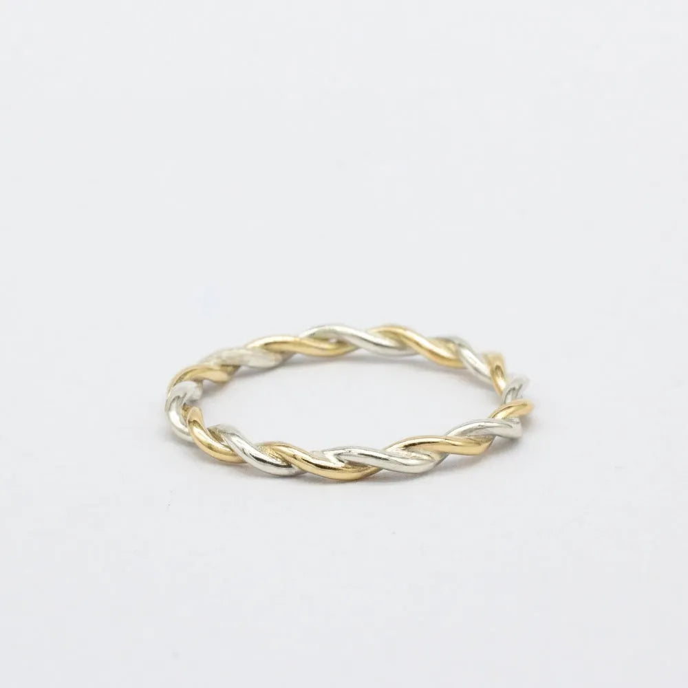 Two-tone gold and silver twisted ring on a light gray background