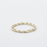 Two-tone gold and silver twisted ring on a light gray background