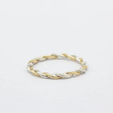 Two-tone gold and silver twisted ring on a light gray background