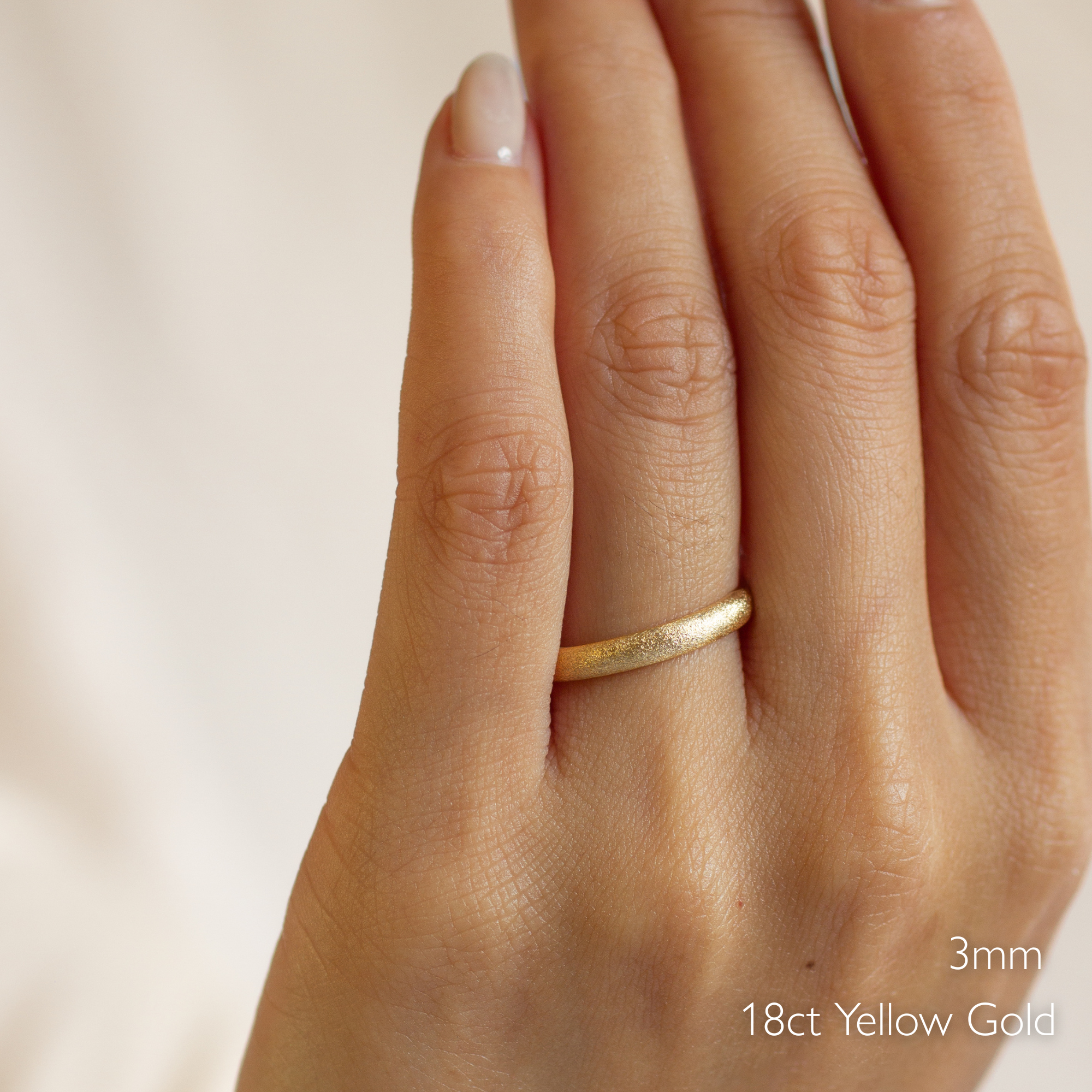 Gold frosted wedding ring on a hand with '3mm 18ct Yellow Gold' text