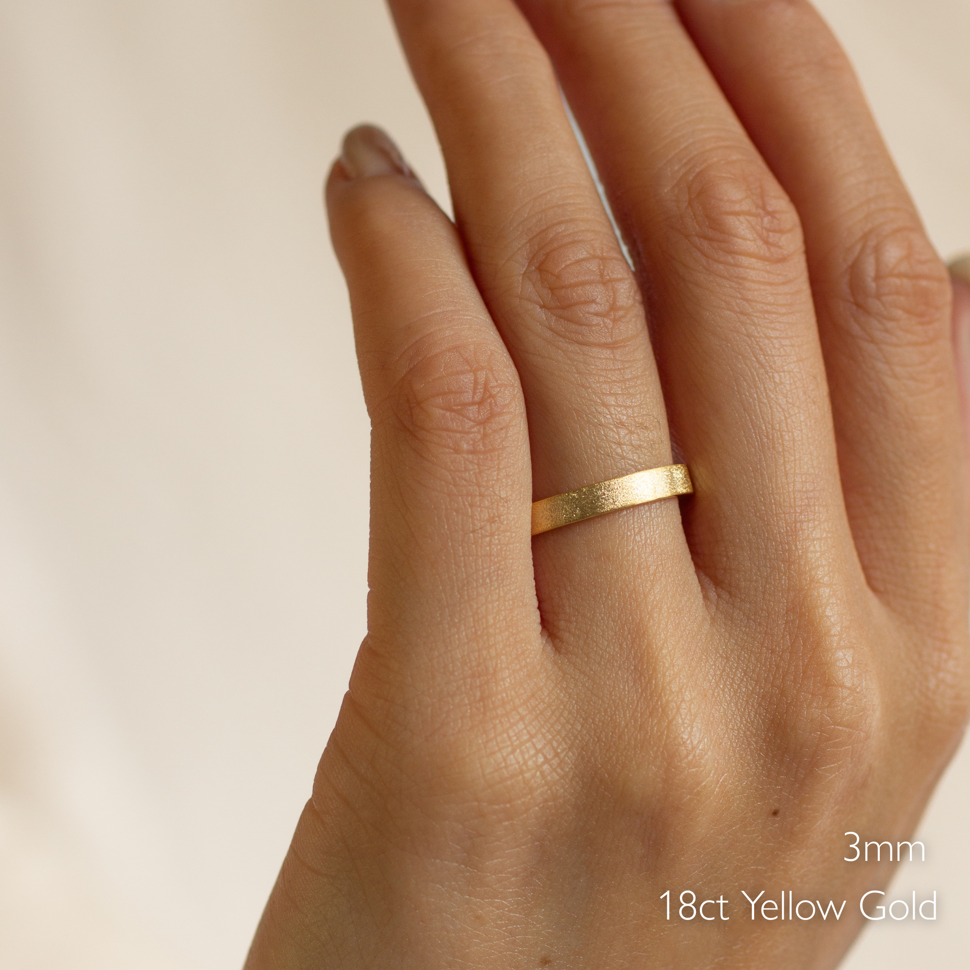 flat frosted matte wedding ring on a hand with '3mm 18ct Yellow Gold' text