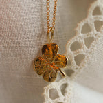 close up of solid gold pendant in 4 leaf clover shape on lace fabric