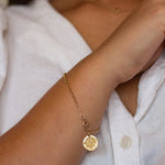 Gold compass bracelet on a wrist with a blurred background