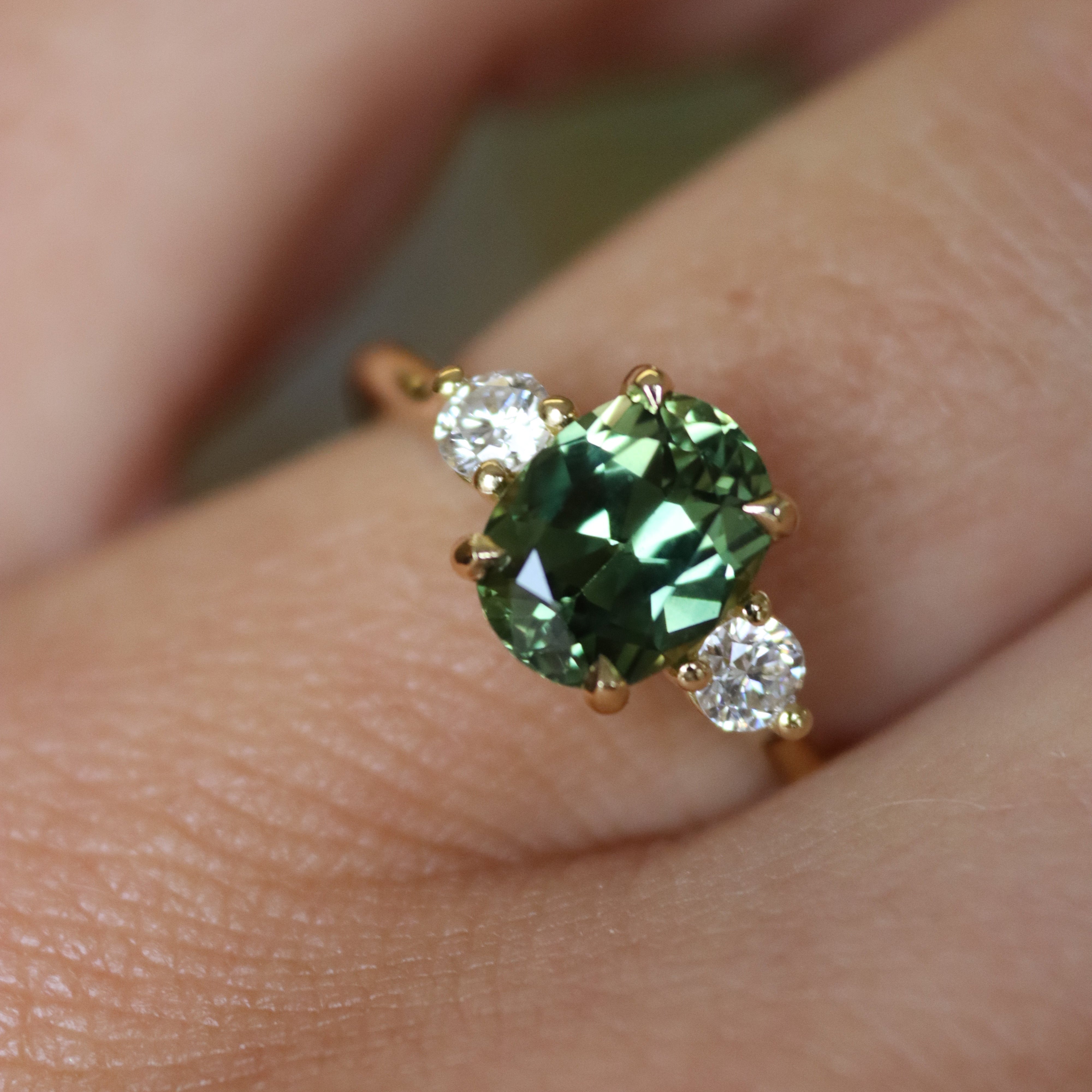 bespoke engagement ring with oval green sapphire and round diamonds