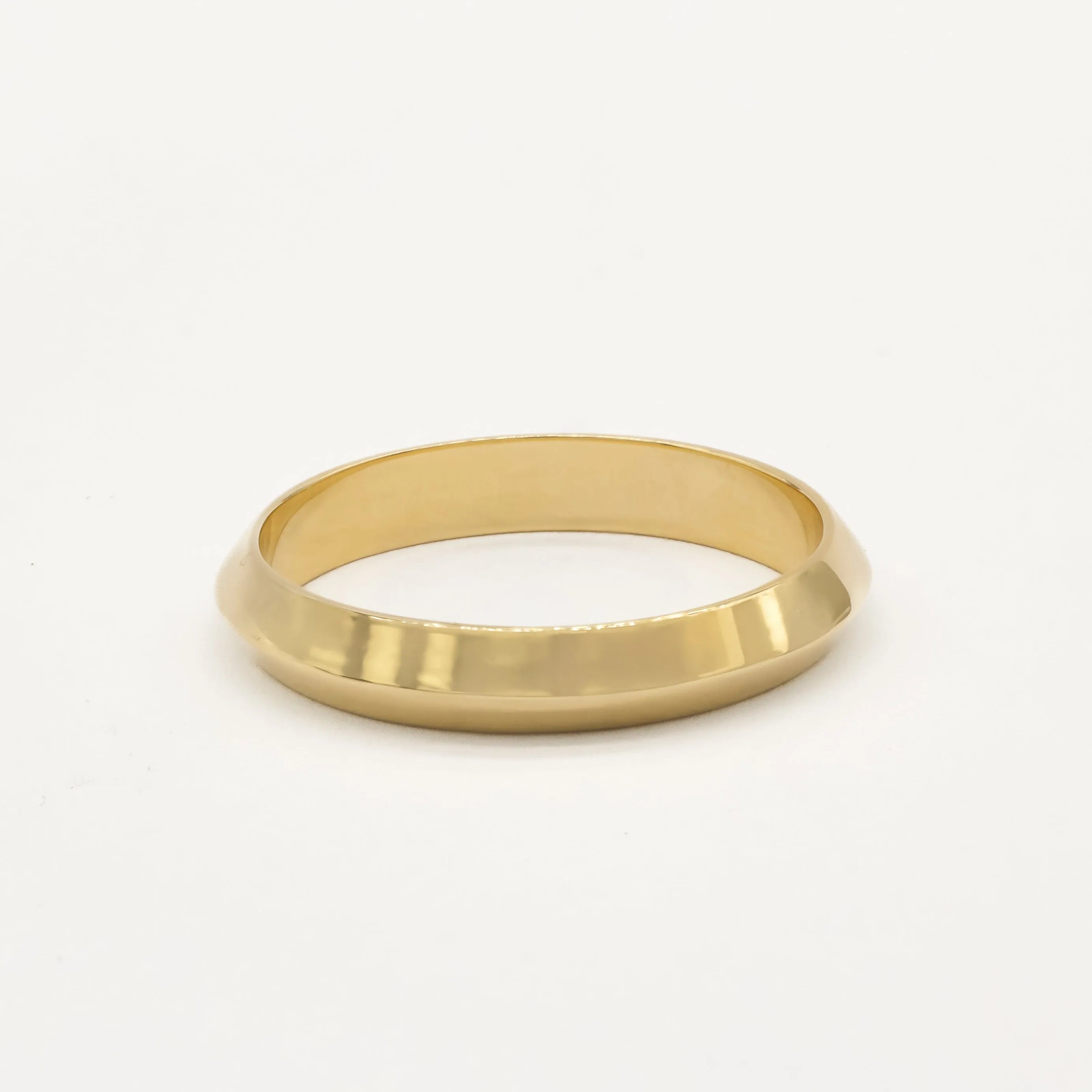 Gold ring with softly pointed knife edge shape on a white background