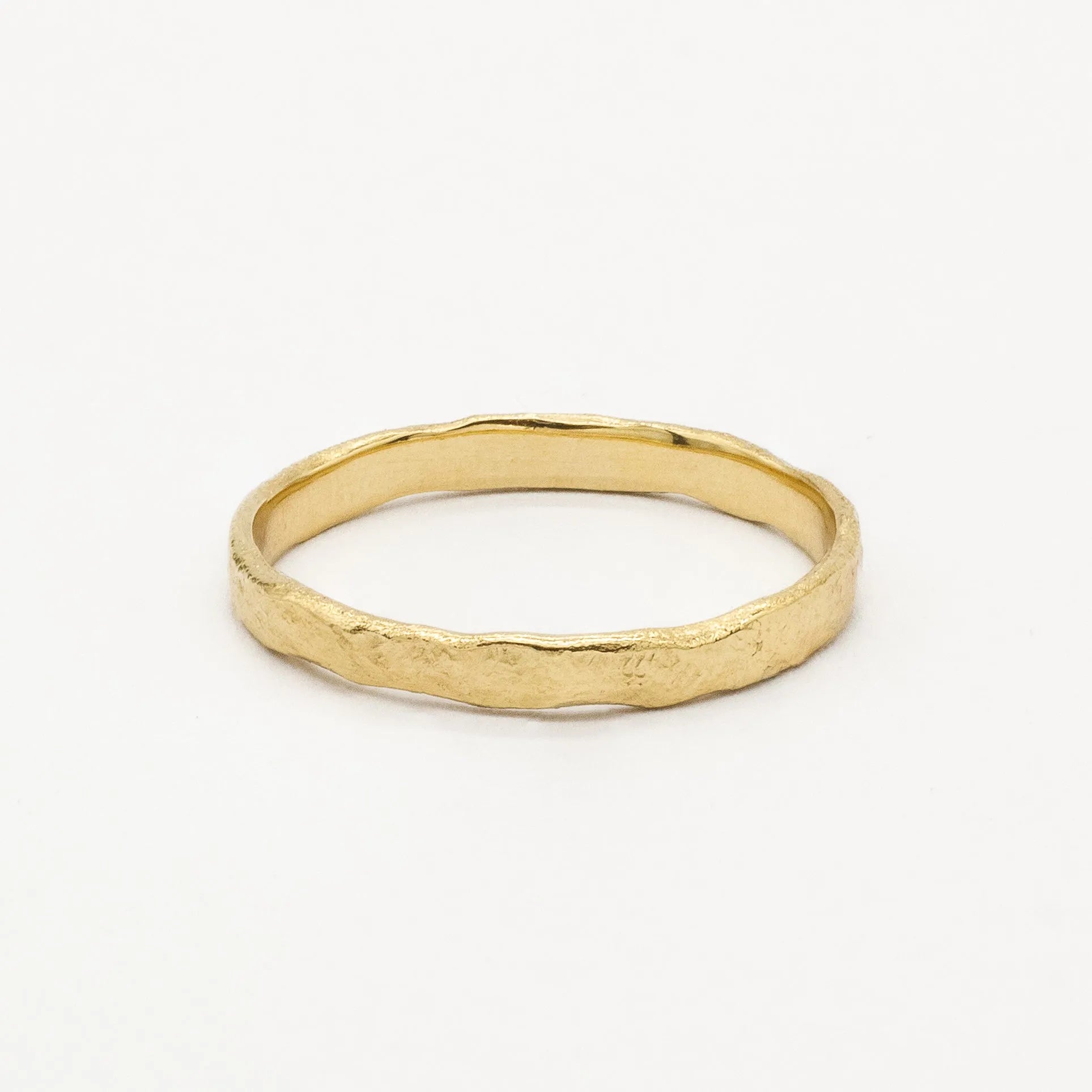 Gold slim 2mm rustic wedding ring with uneven edges and organic finish on a white background