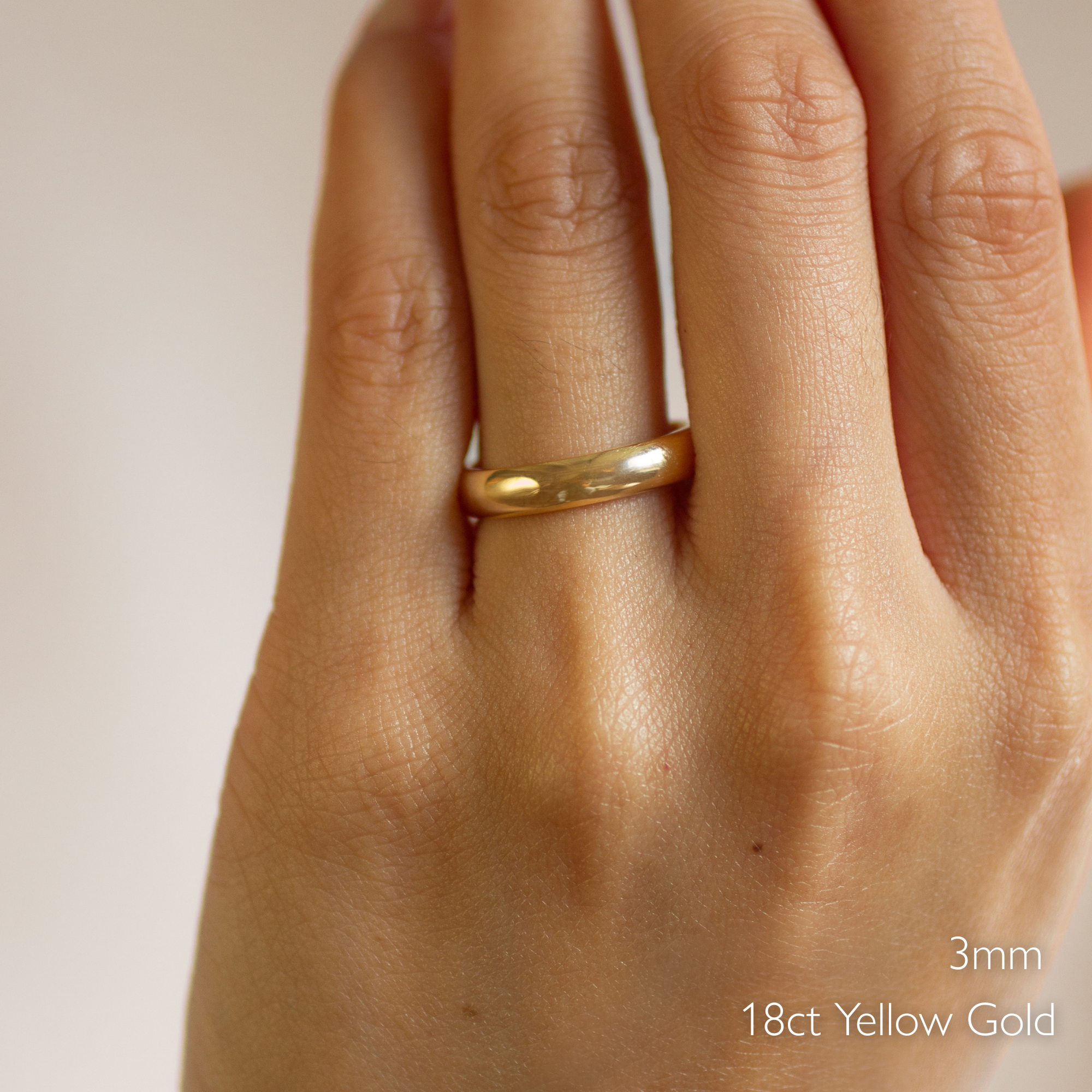 Gold d shape polished wedding ring on a hand with '3mm 18ct Yellow Gold' text