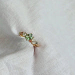 yellow gold engagement ring with cluster of lab-grown diamonds and green and pink sapphires
