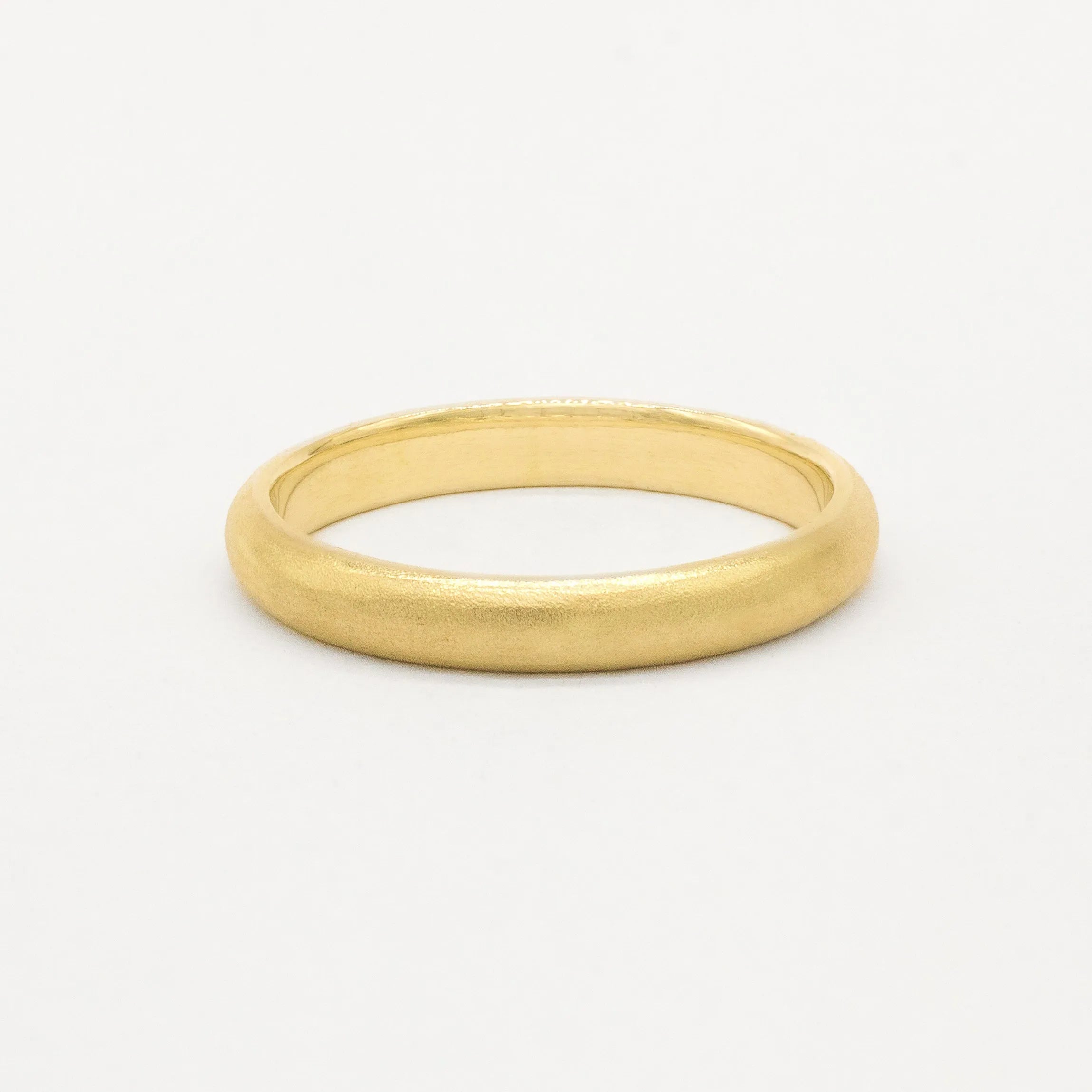 Gold wedding ring with soft satin texture finish on a white background