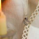 silver 4 leaf clover necklace with candle and lace fabric