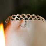 ear cuff on lace fabric with candle flame in foreground