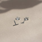 sterling silver hammered bar stud earrings with butterfly backs on beige surface with leaf shadows
