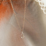 silver number necklace 3 on neutral fabric with warm candle light