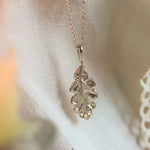silver necklace with oak leaf pendant on neutral fabric