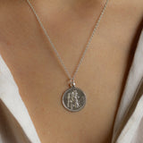 close up of female model wearing silver saint christopher necklace