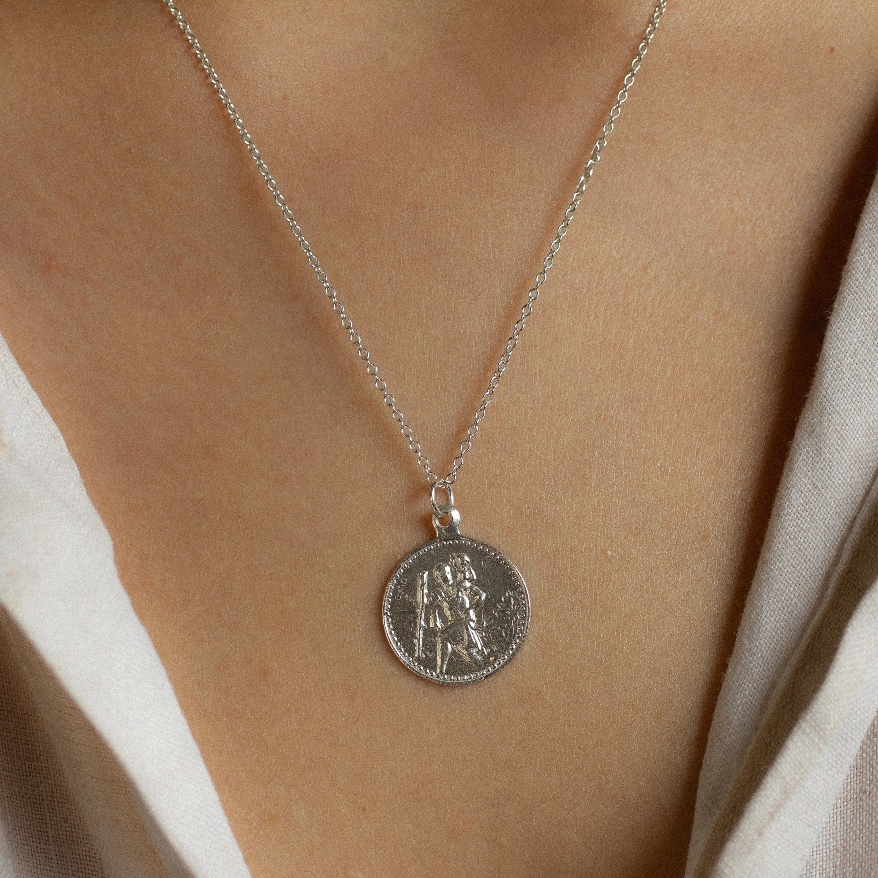 close up of female model wearing silver saint christopher necklace