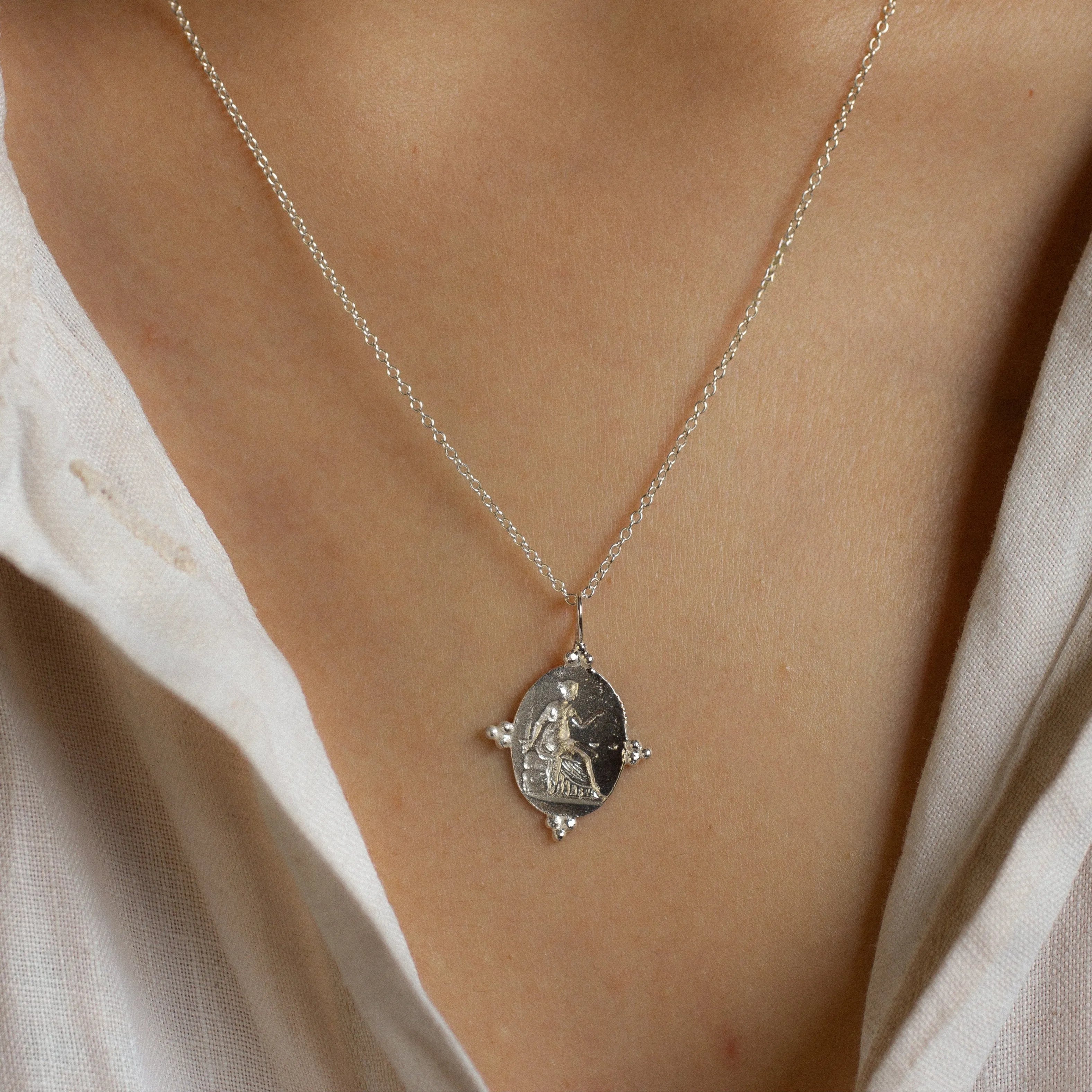 Necklace with a pendant worn by a person wearing a light-colored shirt.
