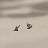 sterling silver triple dot earrings on beige surface with leaf shadows