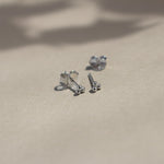 sterling silver triple dot stud earrings with butterfly backs on beige surface with leaf shadows