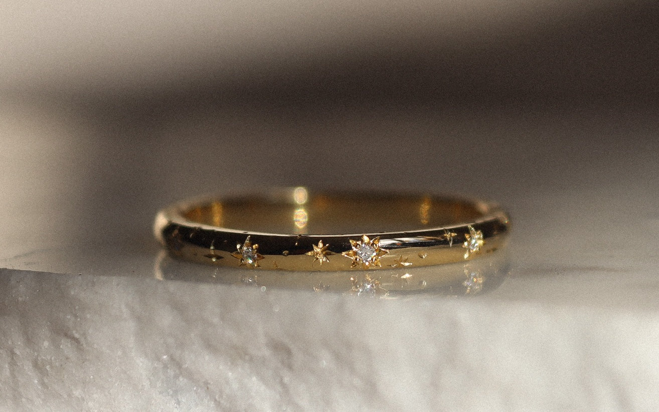 close up of yellow gold wedding ring with star engraving and diamonds