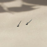 white gold tiny dot studs on beige surface with leaf shadows