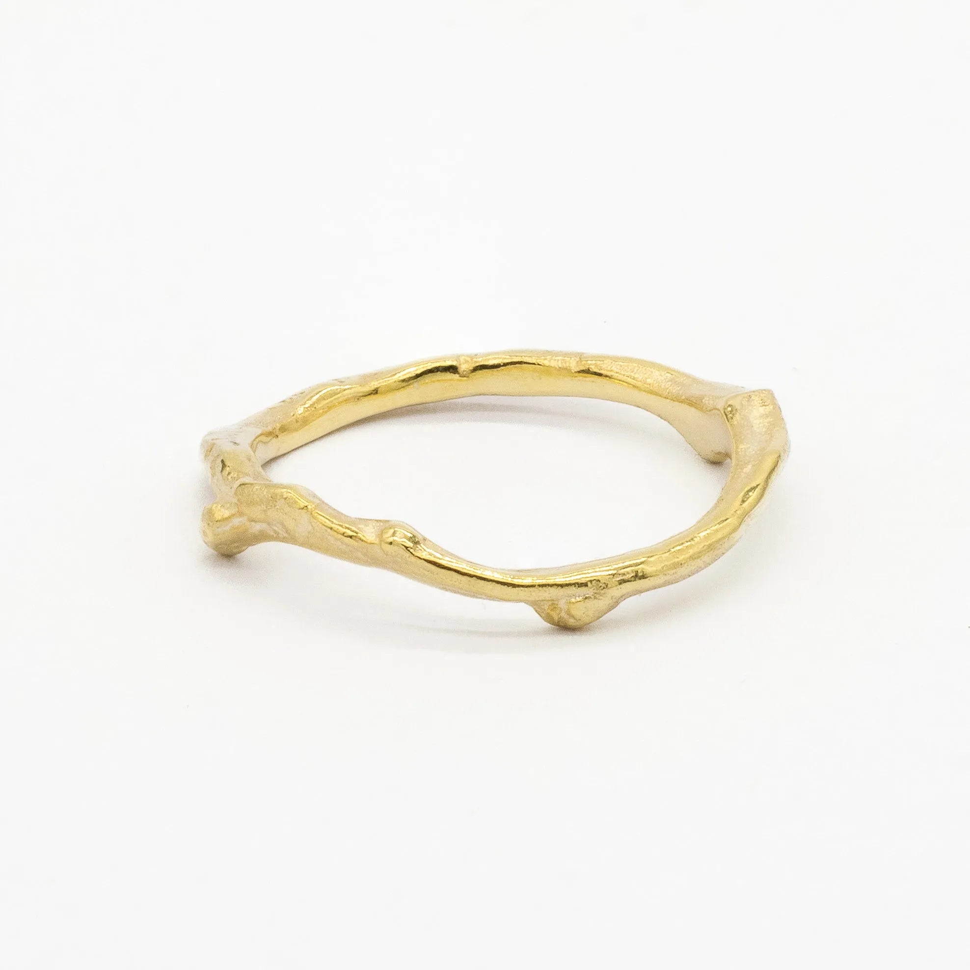 Gold wedding ring with a unique tree branch design on a white background