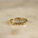 gold ring in leaf vine design on marble surface