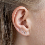 close up of ear wearing three white gold diamond studs