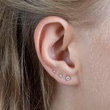 close up of ear wearing yellow gold diamond stacking set featuring 3 diamond studs in different sizes