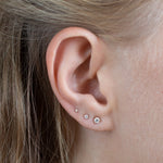 close up of ear wearing yellow gold 3mm diamond stud, 2mm diamond stud and 1.5mm diamond stud