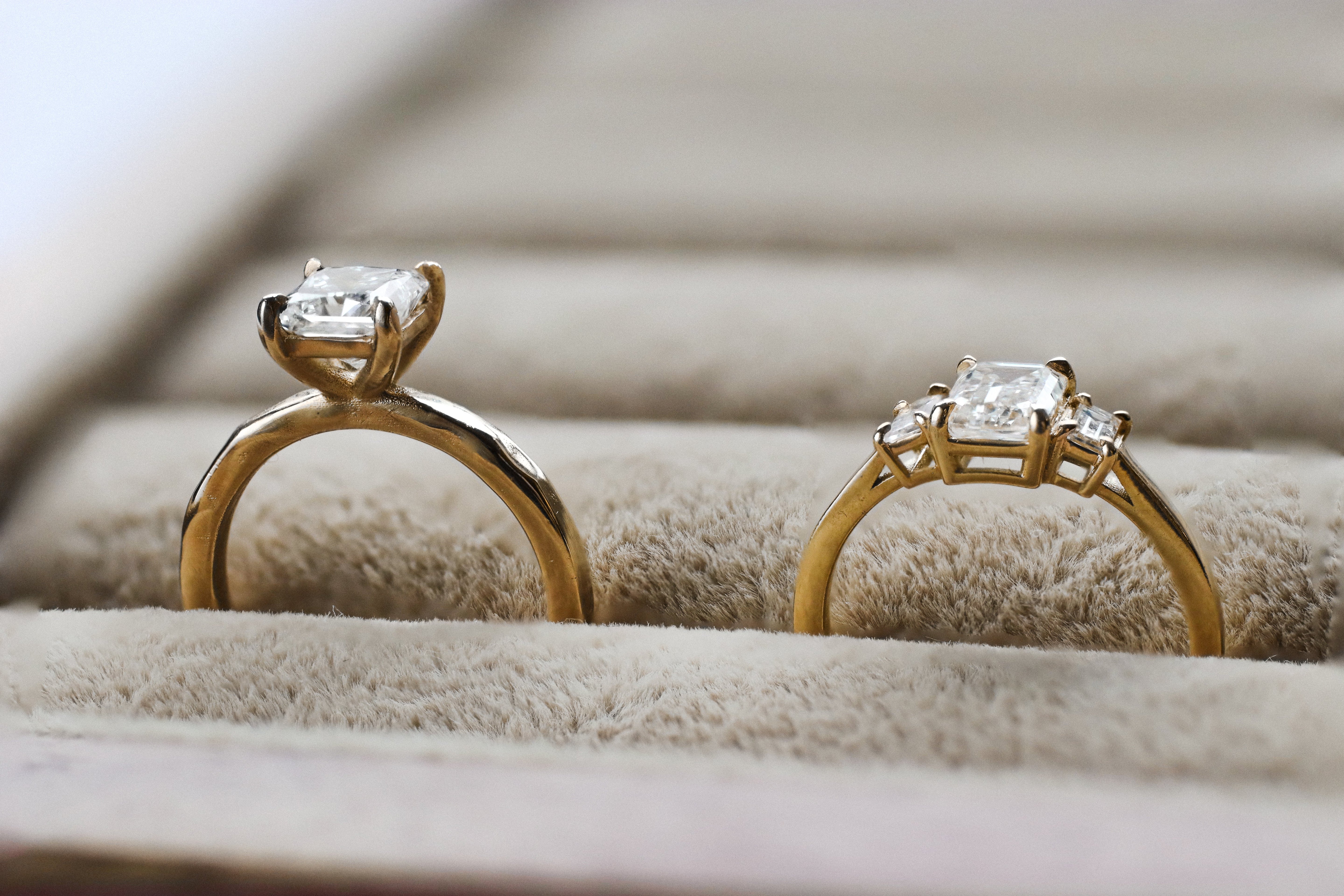side profile of high set diamond engagement ring next to low set diamond engagement ring